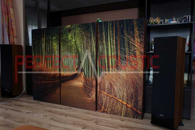 Gedruckte Tafeln zwischen zwei Lautsprechern, die Bilder auf der Tafel stellen einen Waldweg dar