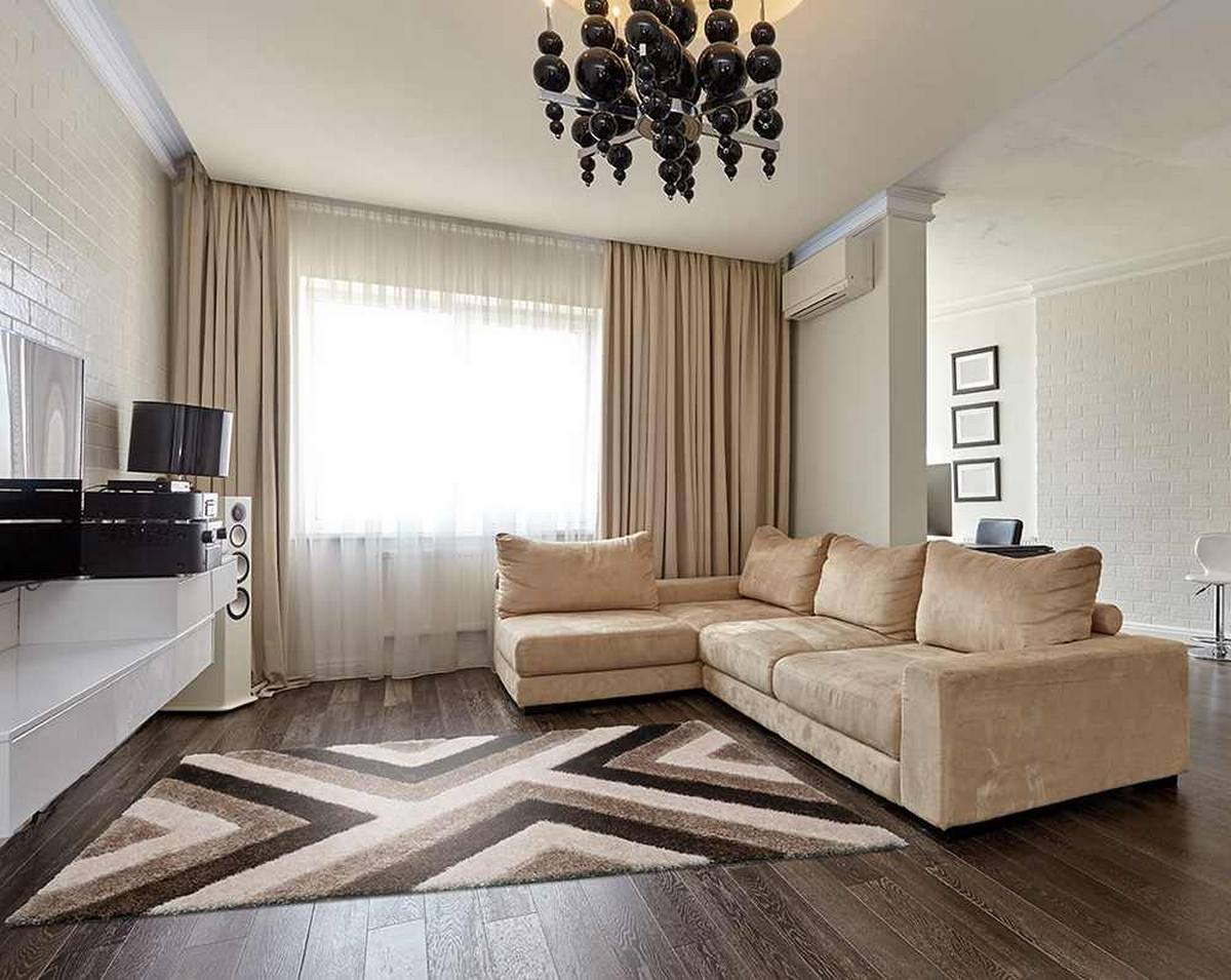 Professional Calm Sharp 3D Akustikteppich mit markantem geometrischem Muster in Creme-, Beige- und Brauntönen in einem modernen Wohnzimmer mit HiFi-Anlage, hellem Ecksofa und bodentiefen Vorhängen.