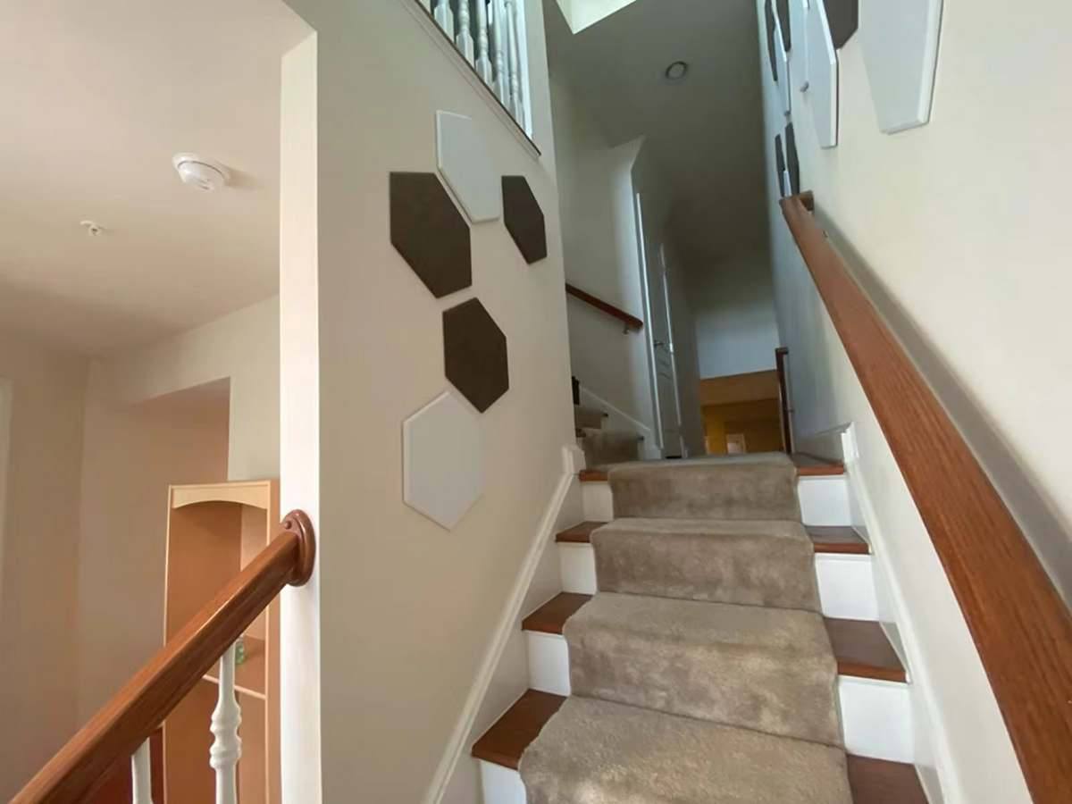 Hexagonale Akustikpaneele in Weiß und Braun an der Wand eines Treppenhauses.Kurzbeschreibung