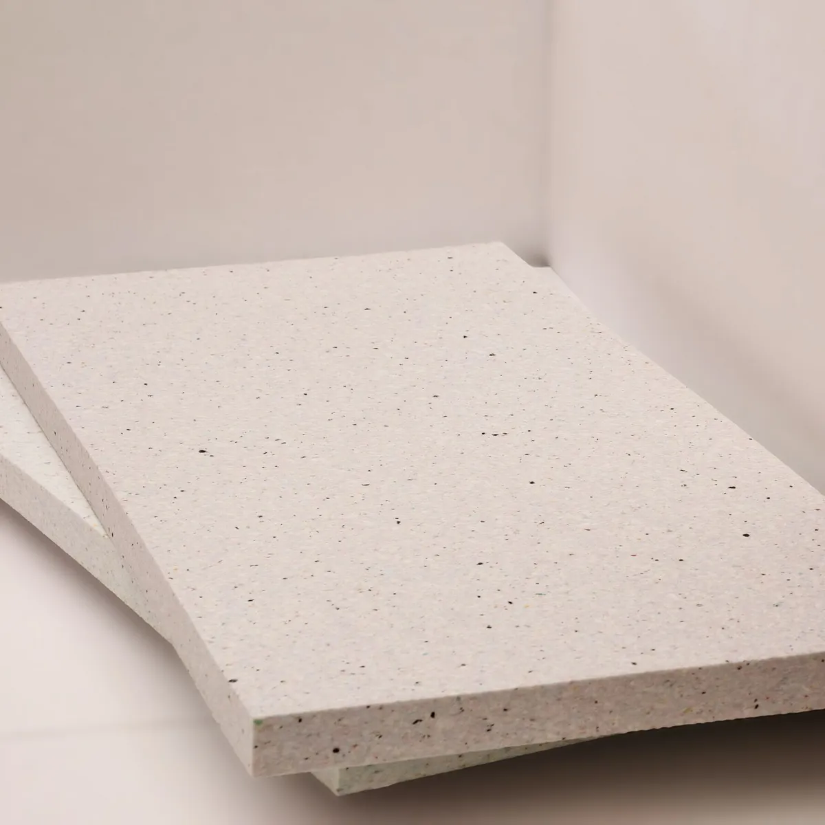 Zwei flammhemmende Elitexa Deckendämmplatten mit hoher Materialdichte und fein gesprenkelter Oberfläche, die ihre stabile Konstruktion und präzisen Kanten zeigen.